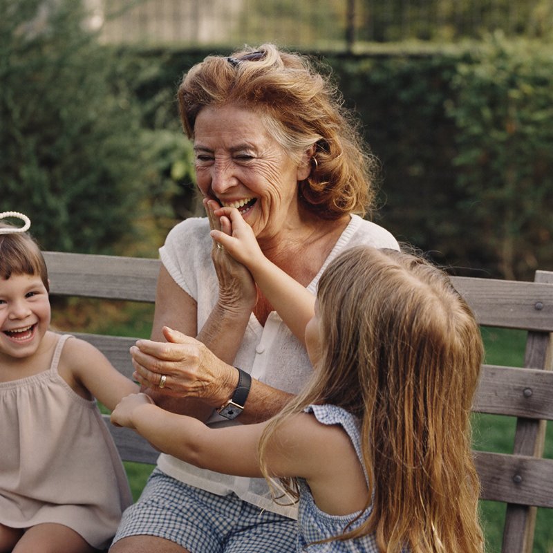 Großmutter spielt lachend mit ihren Enkelkindern im Garten