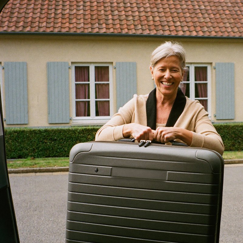 Frau hebt ihren Koffer selbst ins Auto