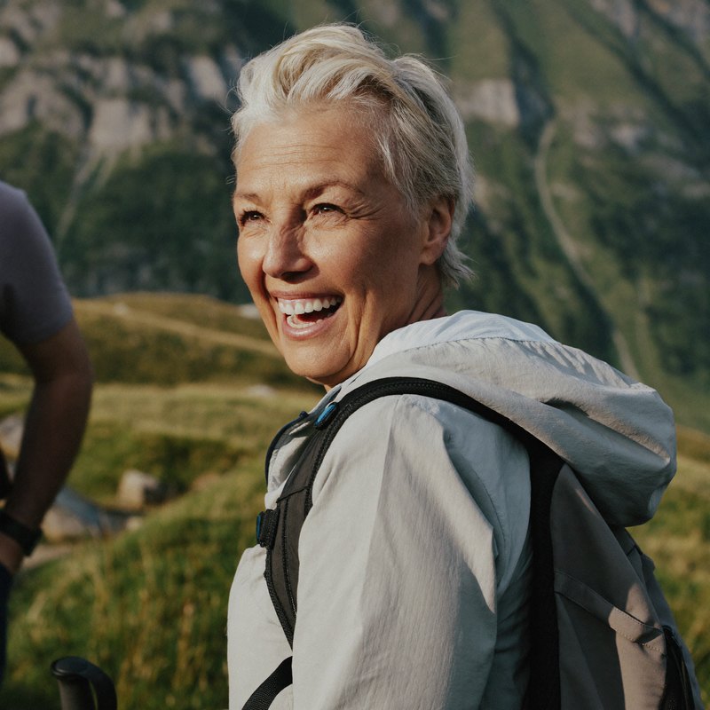 Frau Mitte sechzig lacht beim Wandern in den Bergen
